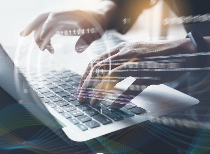 Close-up of hands typing on a laptop keyboard with digital data overlay suggesting online activity or cybersecurity training, blending technology with human interaction.