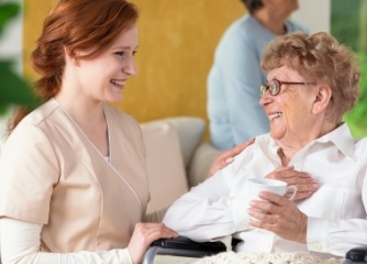 An elderly woman in a wheelchair speaking to a healthcare provider. 