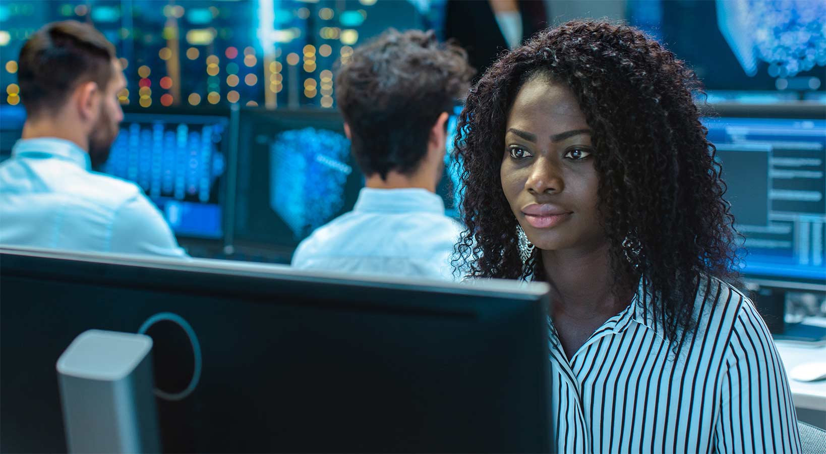 A woman sitting in a computer lab looks intently at a computer screen after learning what you can do with a cyber security degree.