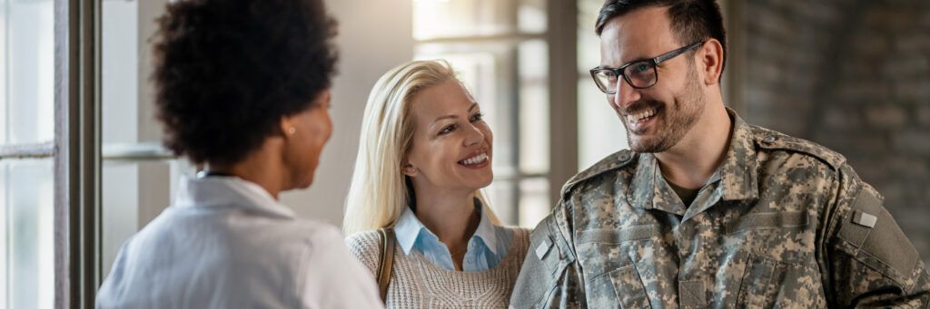 A man in a military uniform speaking to two women.