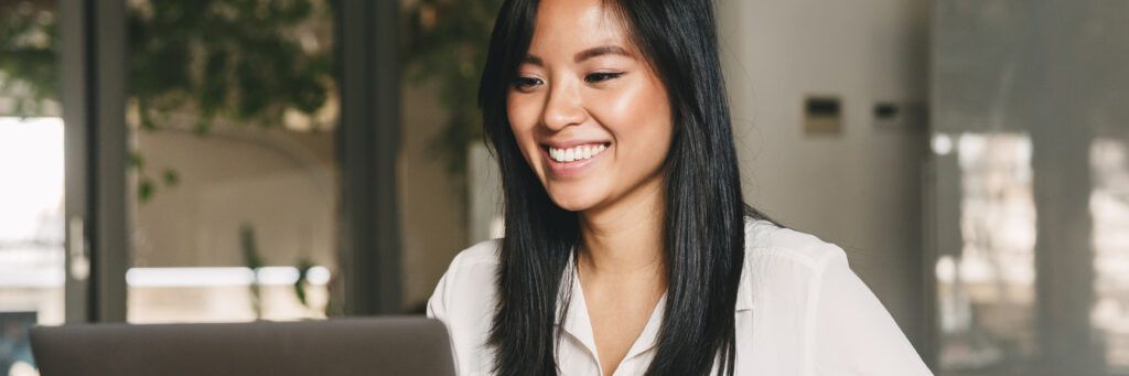 A happy female student working on a laptop.