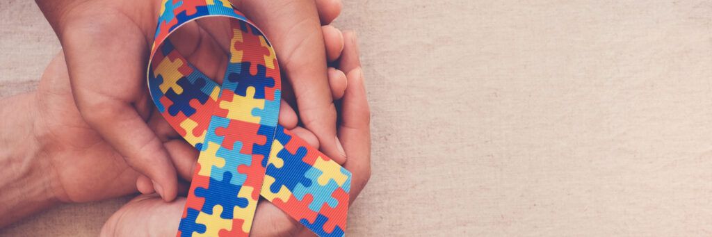 Two sets of hands holding up the Autism ribbon.