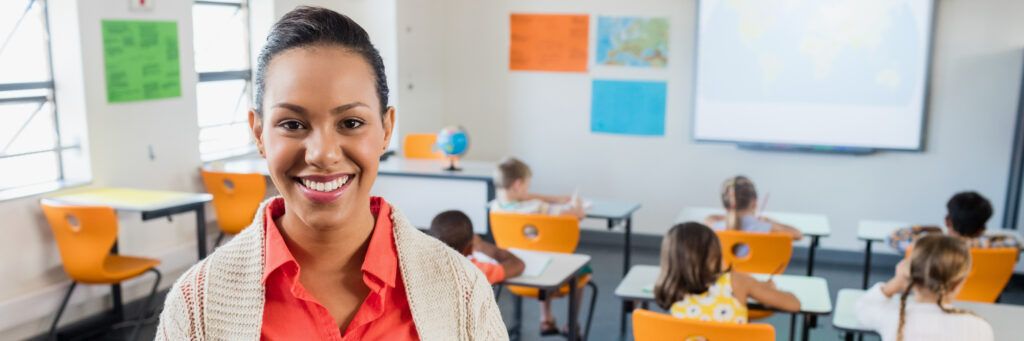 A teacher smiling while her elementary students work at their desks.