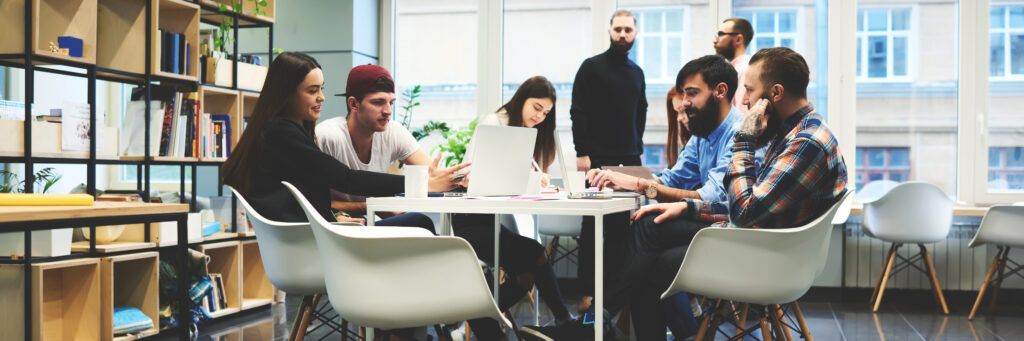 A group of students talking over a table and laptops.