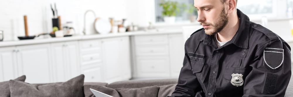 Correctional officer sitting on couch, looking at a laptop.