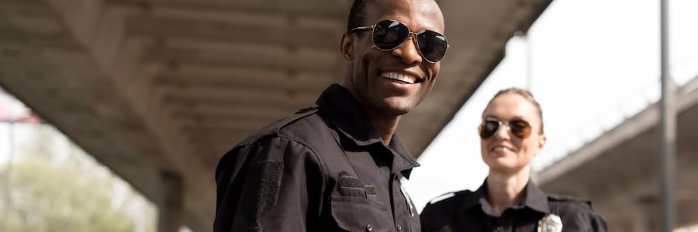 Two police officers smiling and laughing on the side of the highway.