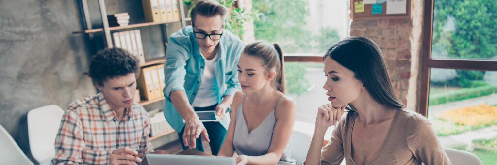 Four students confer in front of laptop.