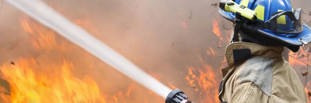 A firefighter works to extinguish flames from a fire by spraying water from a hose.