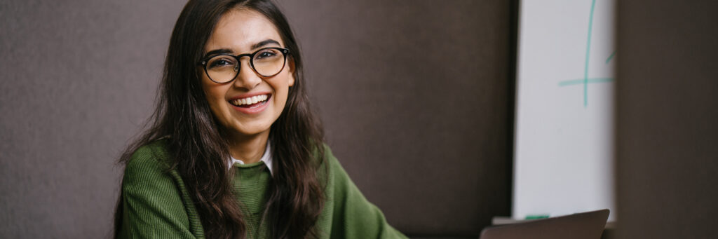 A woman confidently looks into the camera after learning the essential skills for psychology students. 