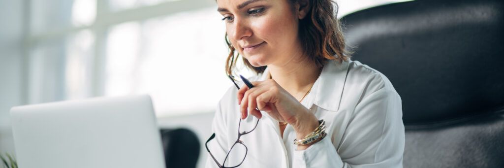 A woman on a laptop considers the best online public administration degree programs.