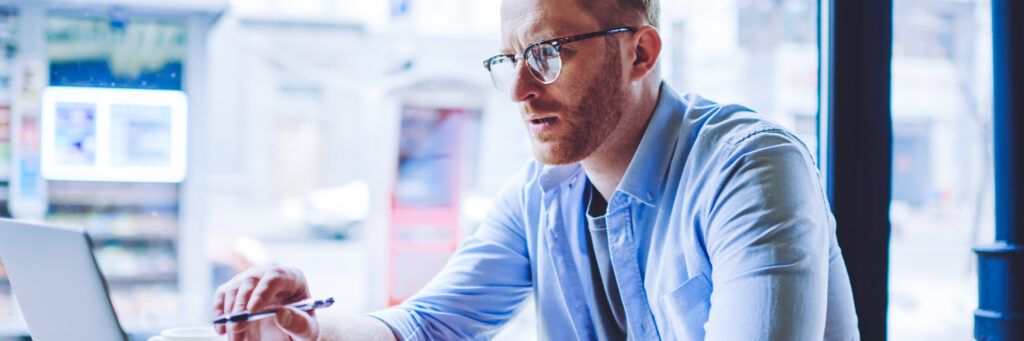 A man looks at a laptop in concentration while studying the top online MSW programs.