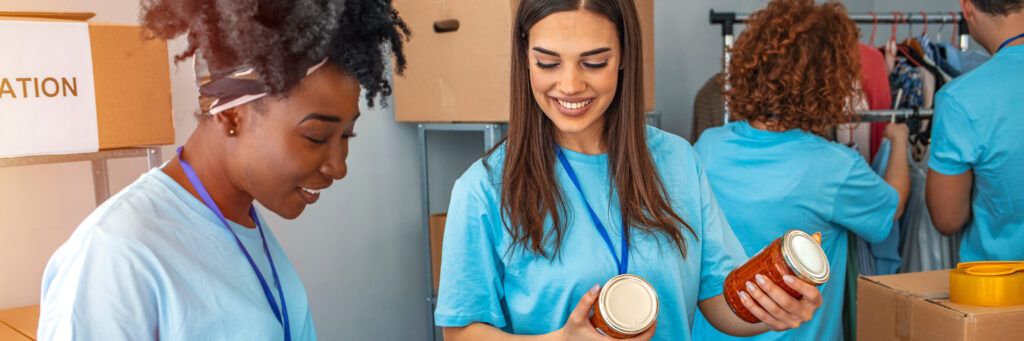 Two smiling women stand side-by-side and unpack cans while discussing the most affordable online MSW programs. 