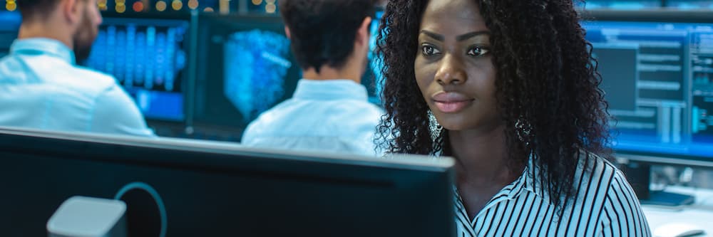 A woman sitting in a computer lab looks intently at a computer screen after learning what you can do with a cyber security degree.