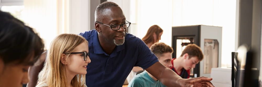 A man leans over a student, pointing to a computer screen to show her what you can do with a public service degree.